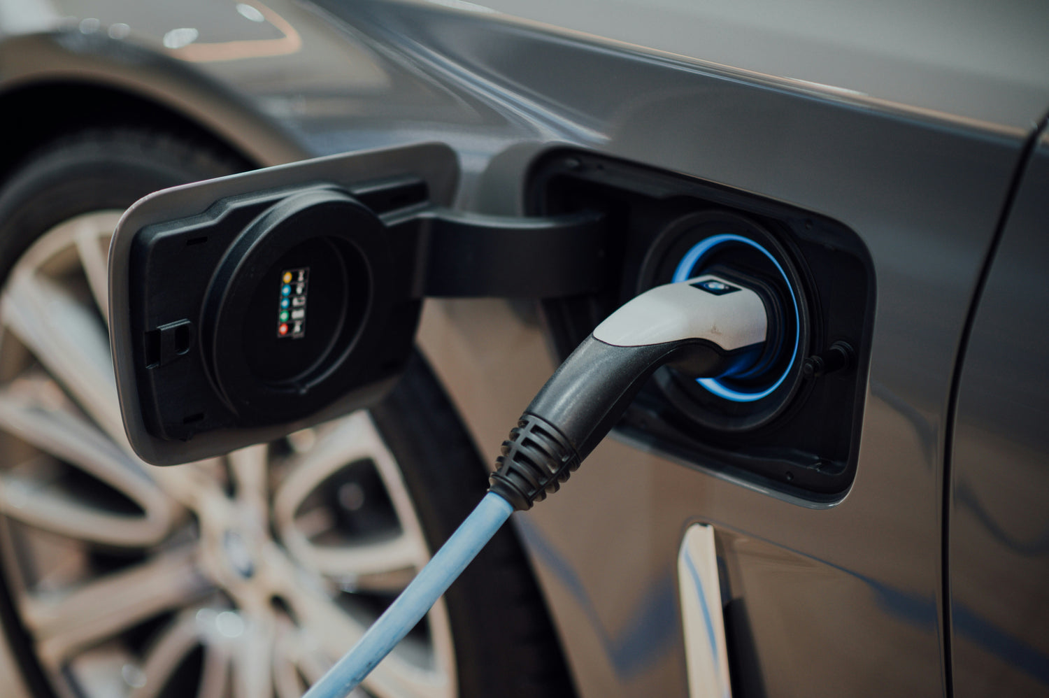 Electric vehicle charging cable plugged into a car's charging port. Electric vehicle charging stations monitored through a smart charging management dashboard.